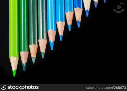 Color pencils in diagonal formation isolated on black background with cool palette. Shot at close-up