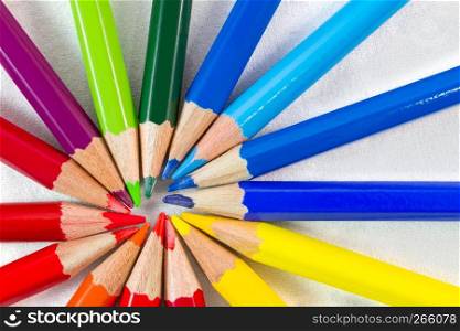 Color pencils in round formation on white background. Shot at close-up with composition center at lower left