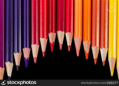 Color pencils isolated on black background in wave formation. Shot at close-up with pencils pointing downwards