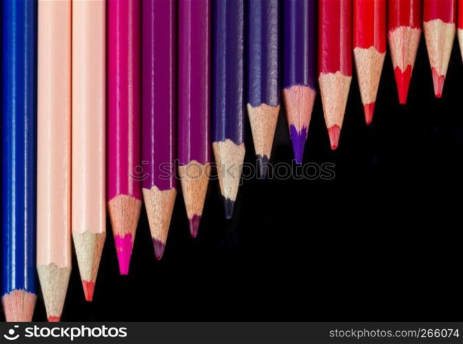 Color pencils isolated on black background with warm palette. Shot at close-up