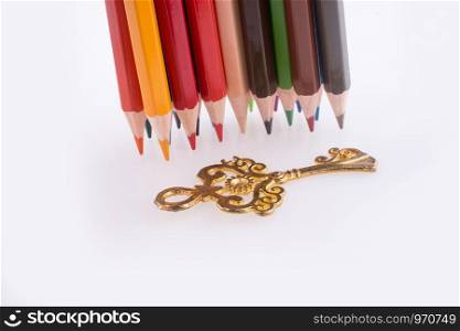 color pencils of various colors near a key on a white background