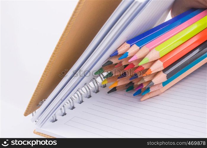 color pencils of various colors near a notebook on a white background