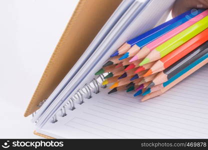 color pencils of various colors near a notebook on a white background