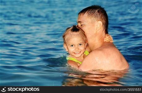 Color photo of father and daughter swimming in the sea