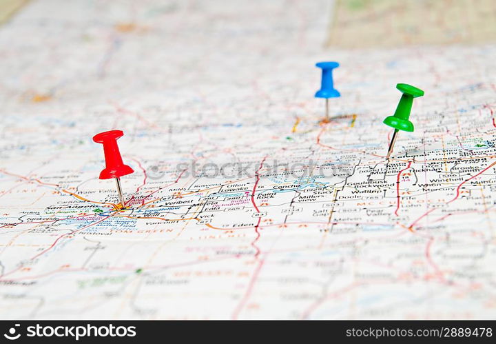 Color pushpins marking a location on a road map.