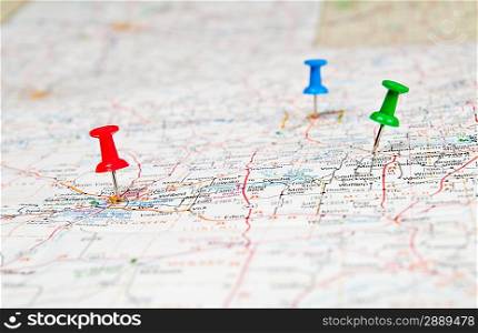 Color pushpins marking a location on a road map.
