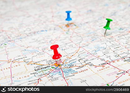 Color pushpins marking a location on a road map.