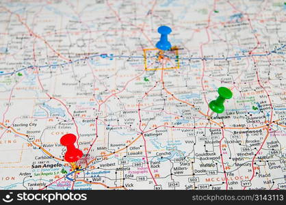 Color pushpins marking a location on a road map. Focused on red pin ( San Angelo)