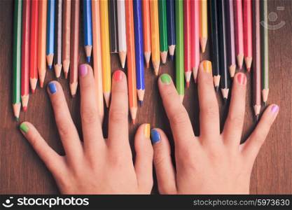 Color rainbow pencils in teenager&amp;#39;s hands with multicoloured nails