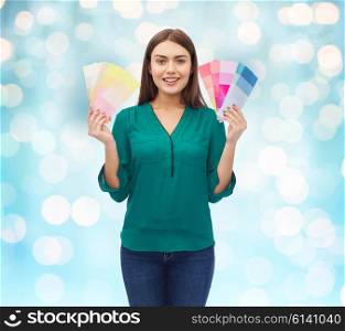 color scheme, decoration, design and people concept - smiling young woman with color swatches or samples over blue holidays lights background