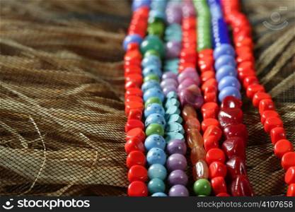 Color stones jewelry necklaces over natural straw and tulle background