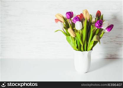 Color tulips in a white vase. Spring concept with copy space. Color tulips in the vase