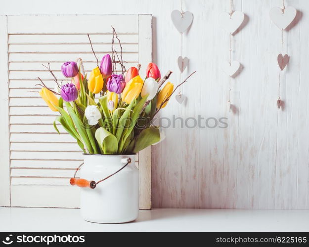 Color tulips with branches in a white cane. Spring decor. Color tulips in the cane