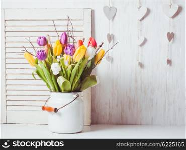 Color tulips with branches in a white cane. Spring decor. Color tulips in the cane