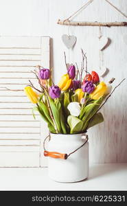 Color tulips with branches in a white cane. Spring decor. Color tulips in the cane