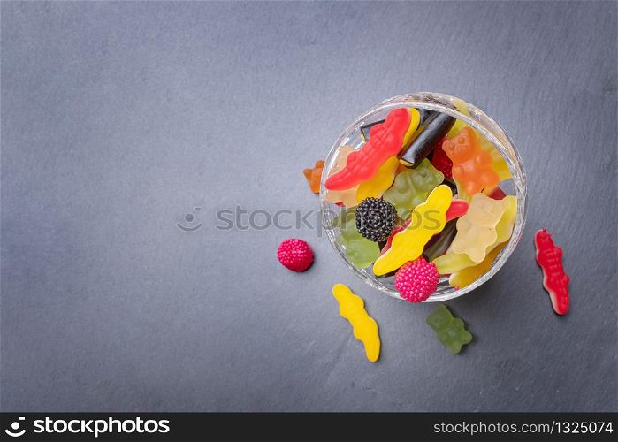 Colored candies inside a glass cup on dark background. Top view with space for your greetings