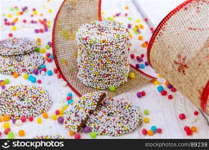 Colored chocolate rings with Christmas decoration on white wood background