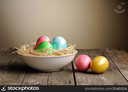 Colored easter eggs in nest on wooden table