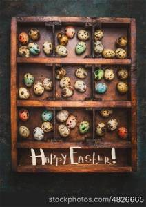 Colored eggs for Easter feast in aged Wooden box on dark rustic background with lettering Happy Easter, top view