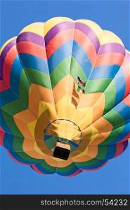 Colored hot-air balloon in flight seen from below against a blue sky. Colored hot-air balloon in flight seen from below