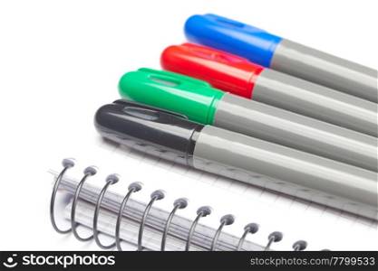 colored markers and a notebook isolated on white