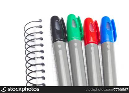 colored markers and a notebook isolated on white