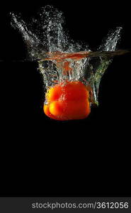 Colored orange paprika in water splashes on black background