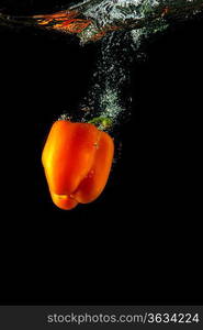 Colored orange paprika in water splashes on black background