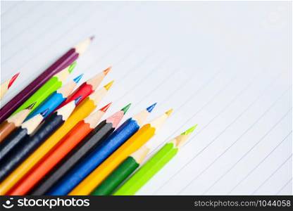 Colored pencil set on white paper notebook back to school and education concept / Crayons colorful