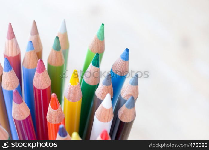 Colored pencils in a can on rustic wooden table, white background