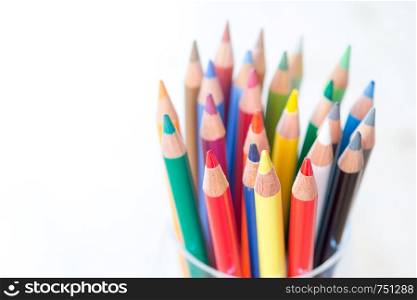 Colored pencils in a can on rustic wooden table, white background