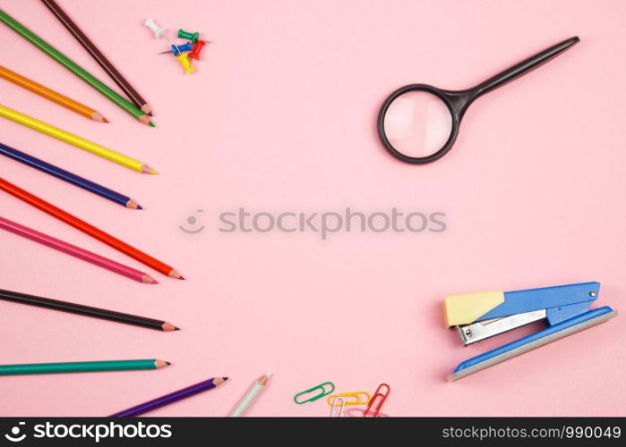 colored pencils, stationery and magnifier on pink isolated background. top view. flat lay. mockup