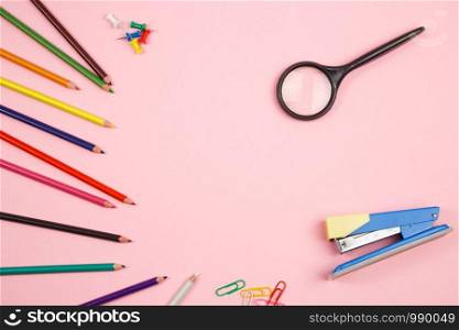colored pencils, stationery and magnifier on pink isolated background. top view. flat lay. mockup