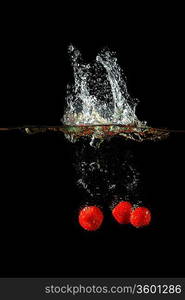 Colored red paprika in water splashes on black background