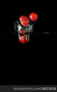 Colored red paprika in water splashes on black background