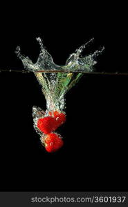 Colored red paprika in water splashes on black background