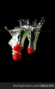 Colored red paprika in water splashes on black background