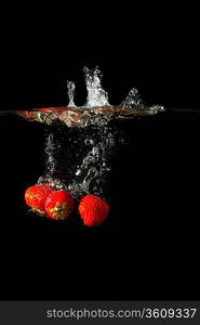 Colored red paprika in water splashes on black background