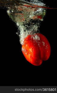 Colored red paprika in water splashes on black background