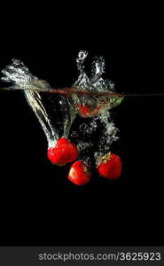 Colored red paprika in water splashes on black background