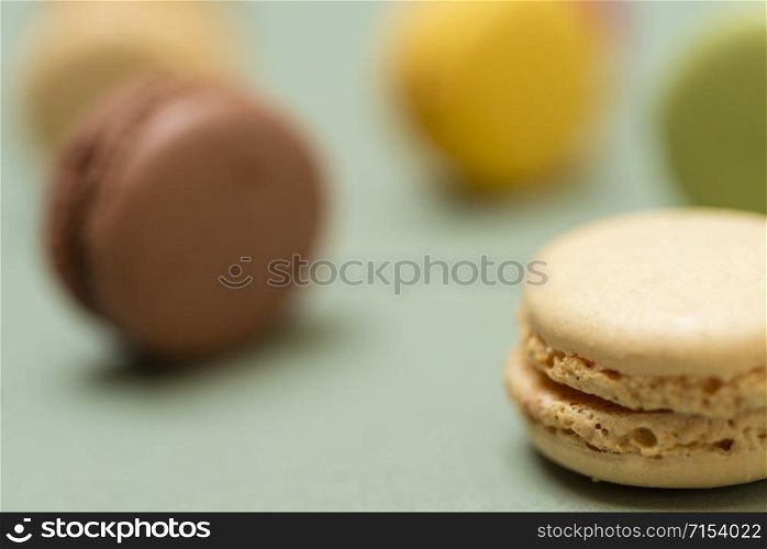 Colored tasty macaroons over a green background.