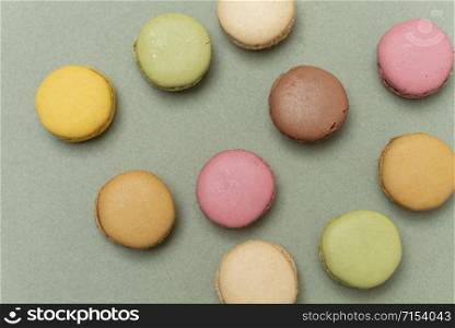 Colored tasty macaroons over a green background.