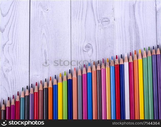 Colored wooden pencils, arranged in the form of a ladder, on a gray and white background. education concept.