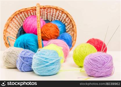 colored woolen thread crumbled from wicker basket close up on a white background