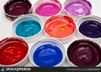 Colorful acrylic paints in covers isolated on table