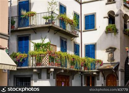 Colorful and ancient house with many flowers and plant at the balcony,in the historic centre of the Pisogne town.