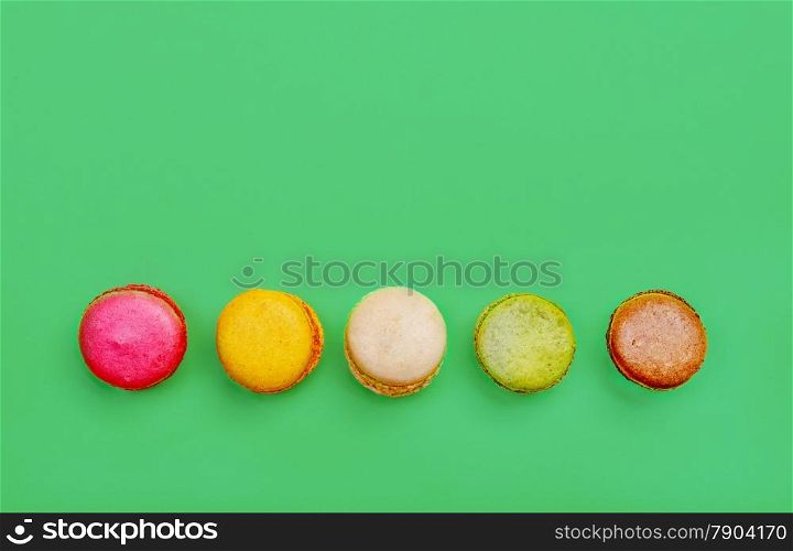 Colorful and tasty French Macarons on green background.Top view.