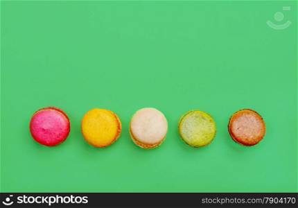 Colorful and tasty French Macarons on green background.Top view.