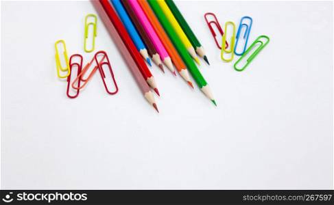Colorful art and drawing concepts, Crayon pencils and clips at top corner on white background with copy space. Wide web banner, poster, brochure template design. Top view, Closeup.