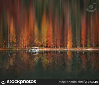 Colorful autumn forest with motion blur artistic effect, reflected in the water of the Alpsee lake, near Fussen city, Germany.